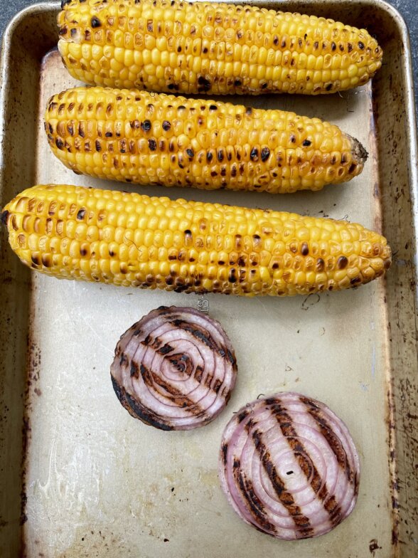 grilled corn and onions on a baking sheet