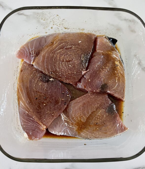 ahi tuna steaks marinating in a glass bowl