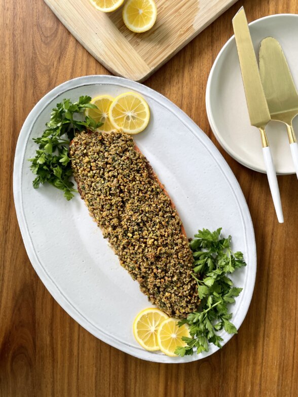 a finished salmon filet on a white plate with garnish