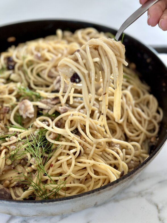 a fork lifting pasta out of a skillet