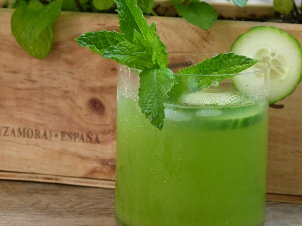 a single cocktail topped with cucumber and mint