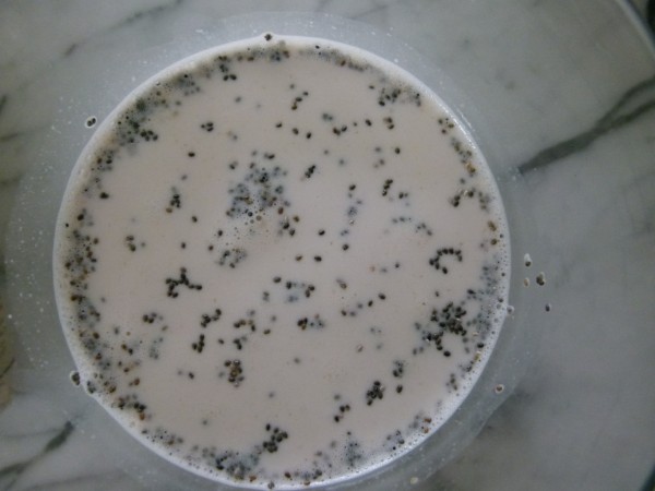 Close-up of a glass jar filled with overnight chia oat porridge on a white countertop.
