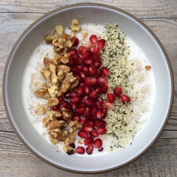 a bowl of porridge with walnut, pomegranate seed and hemp heart toppings