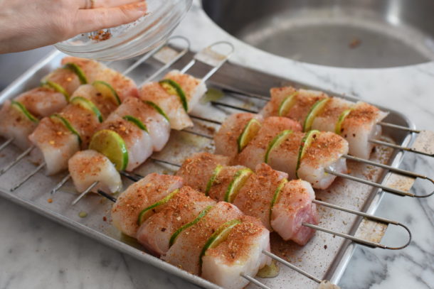 Skewered halibut brushed with olive oil and spices, prepared for grilling.