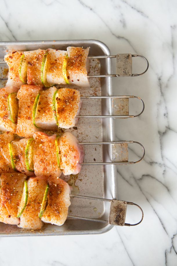 Close-up of fresh halibut and lime slices threaded onto skewers before grilling.