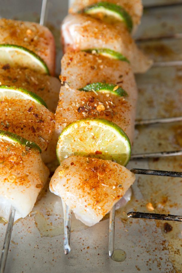 close up of Halibut skewers grilling on a barbecue with visible char and golden edges.