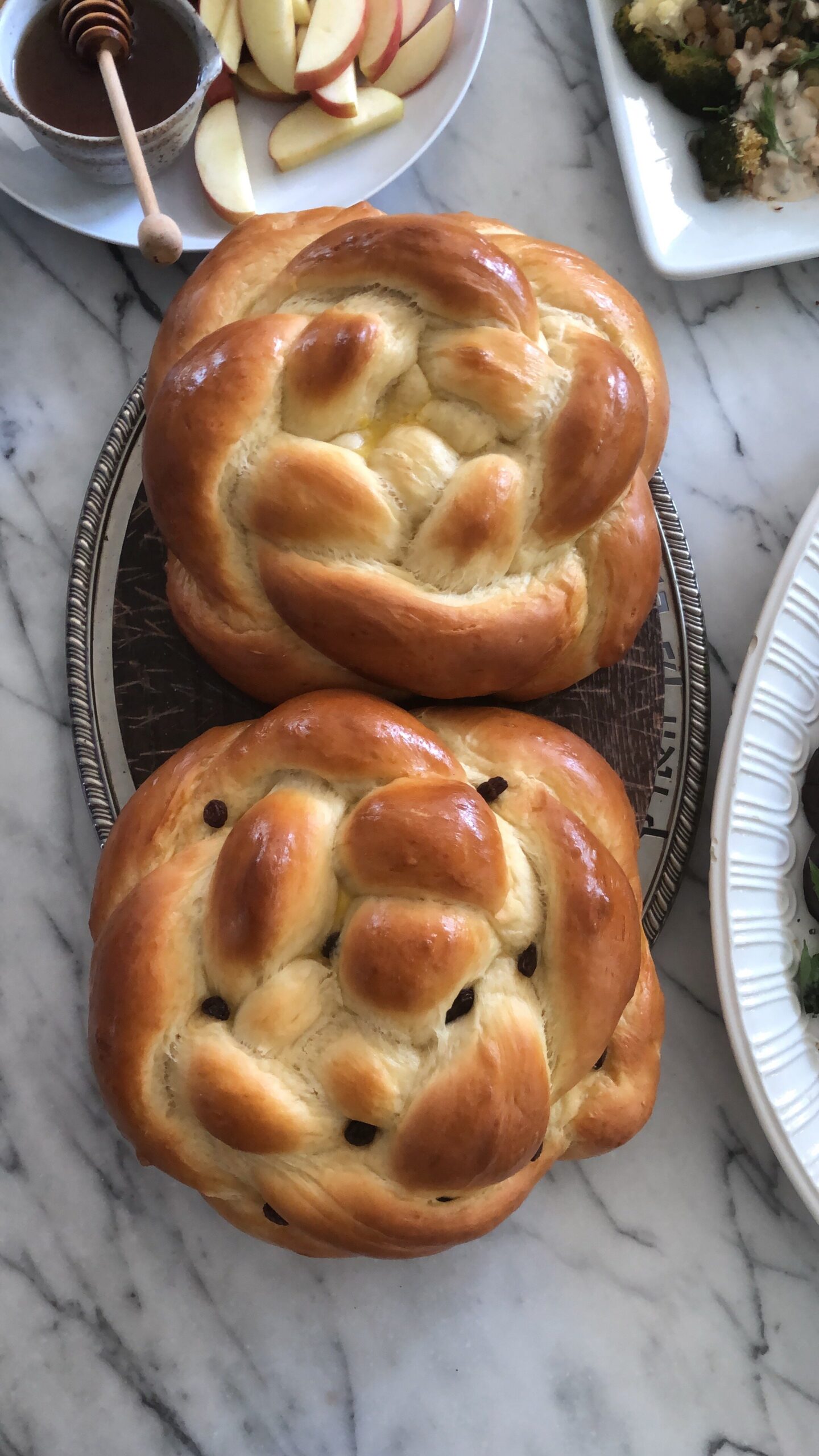 Round challah loaves on a silver tray