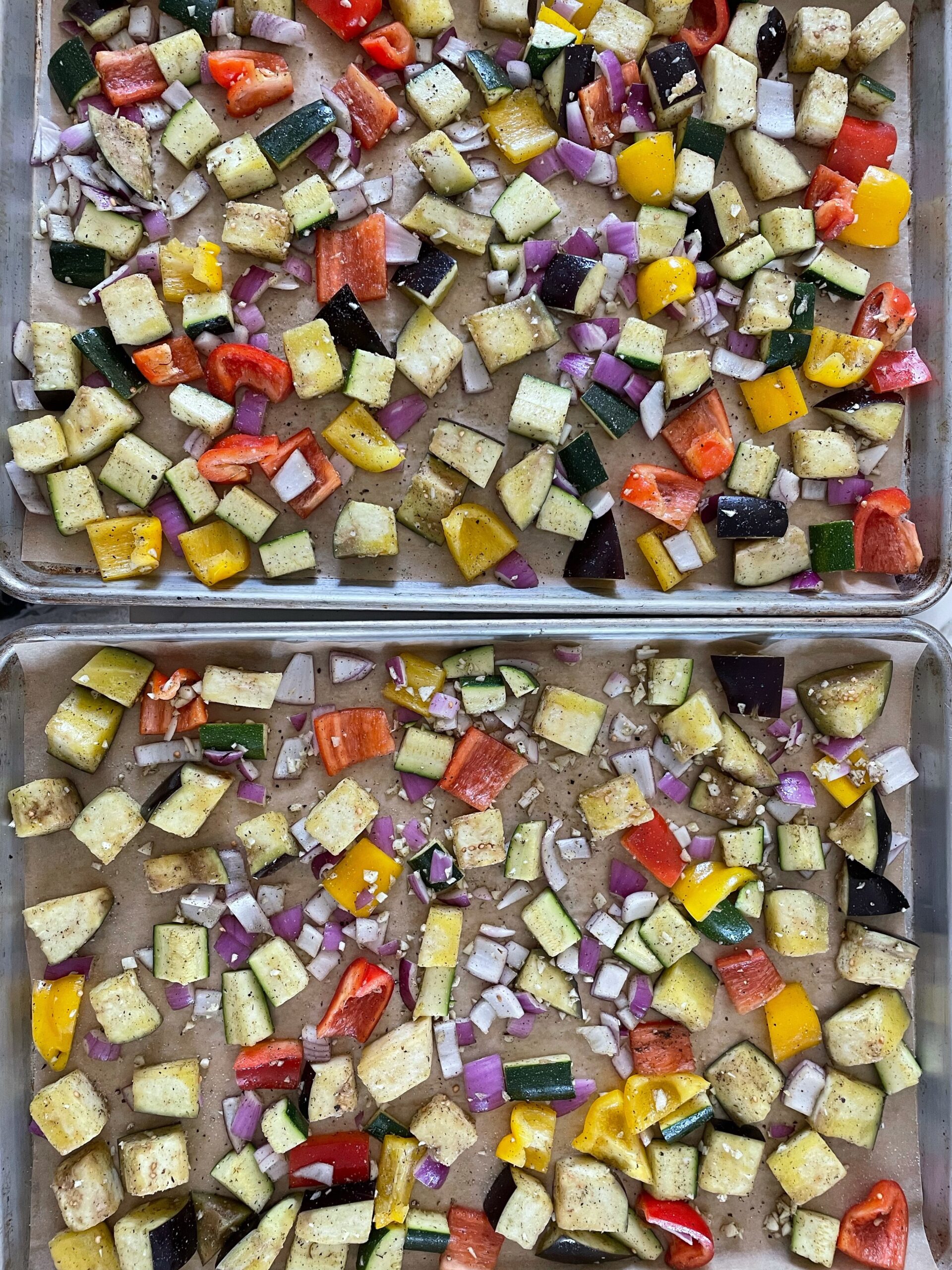 Seasoned vegetables spread on a parchment-lined baking sheet in a single layer.