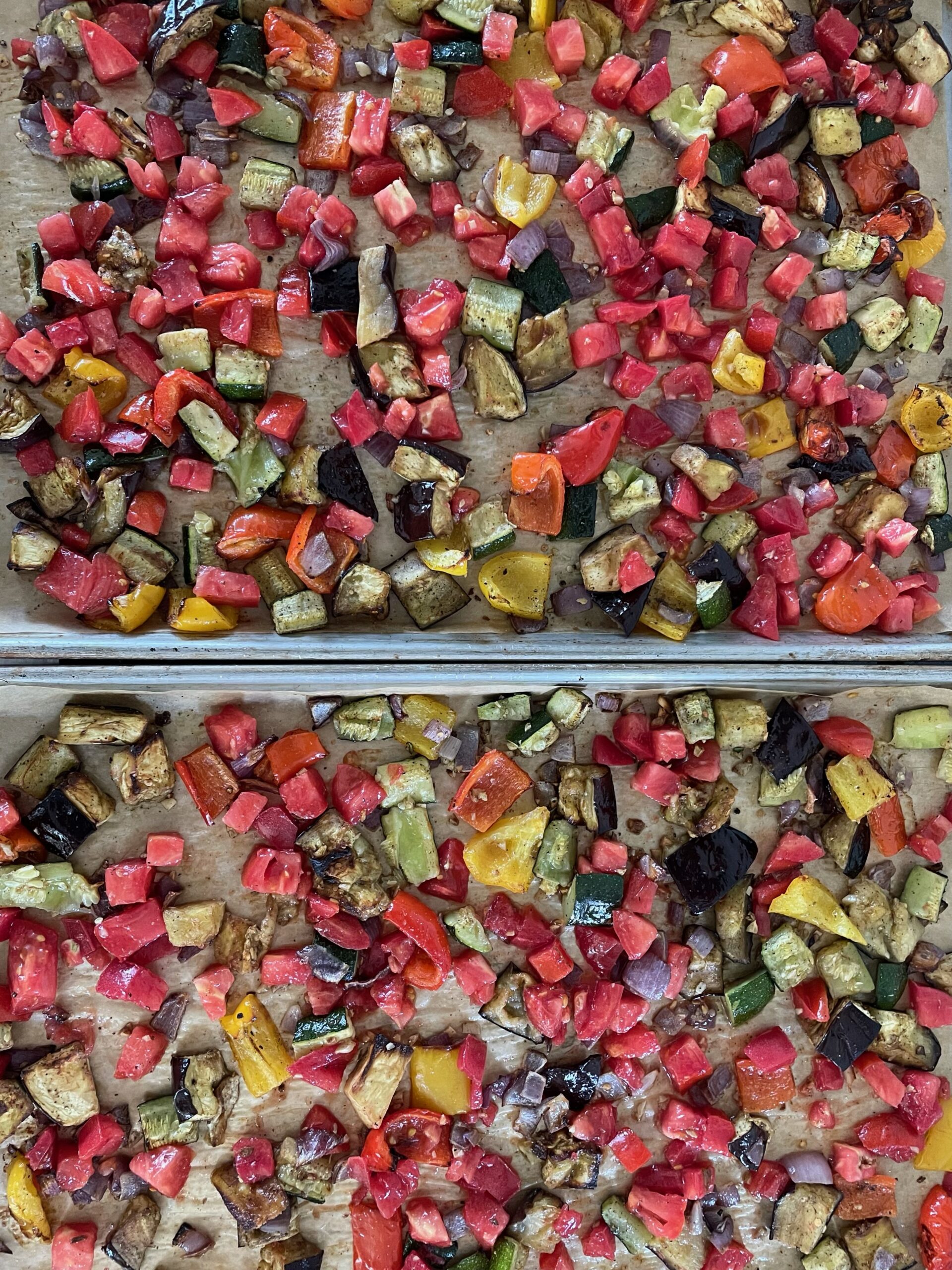 Roasted vegetables on a baking sheet starting to caramelize.