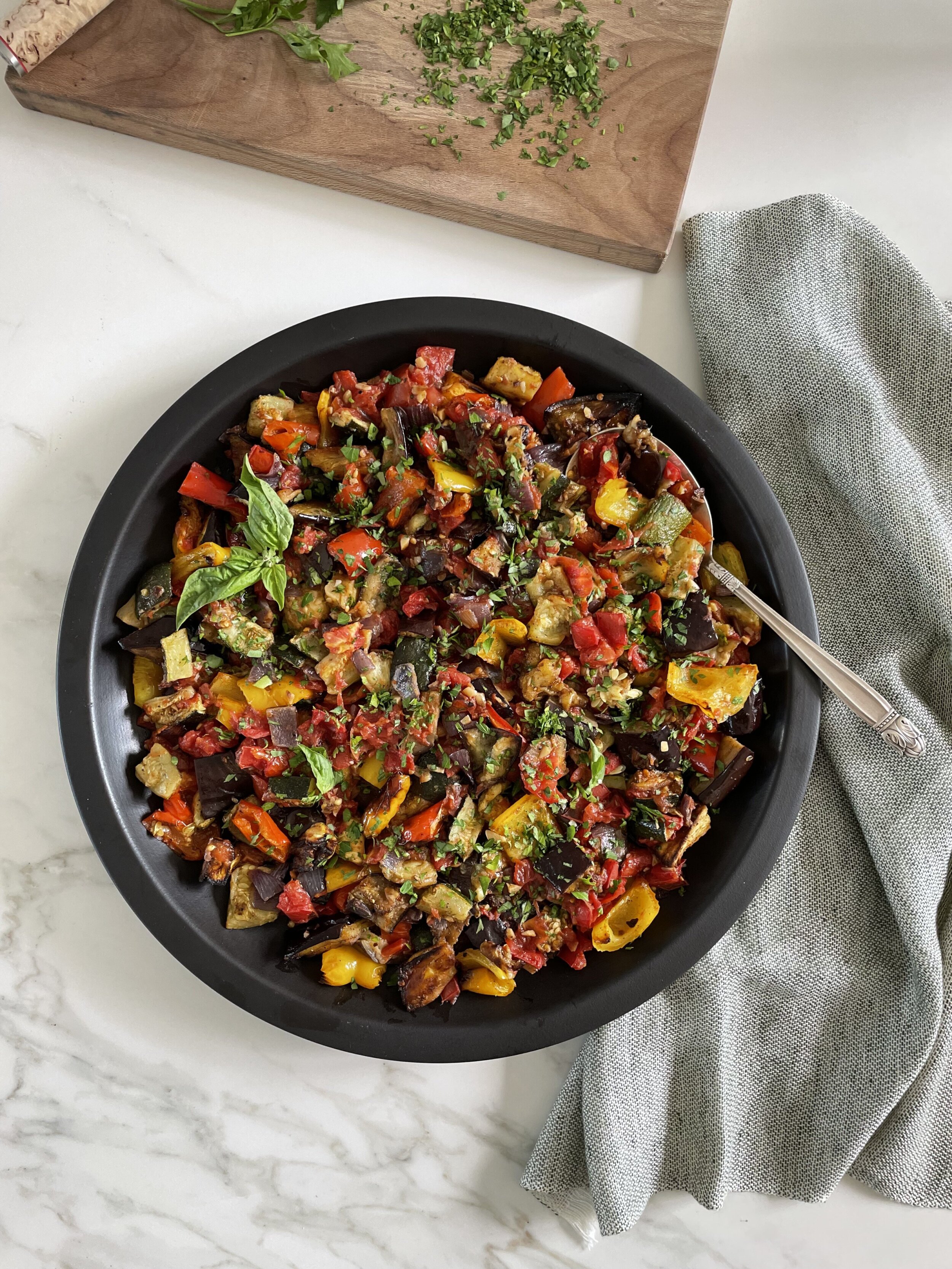 Finished ratatouille in a black serving dish, garnished with basil.