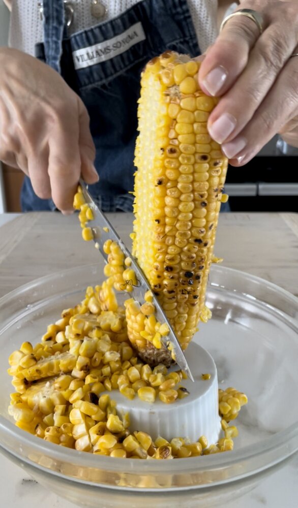 a hand slicing corn off the cob