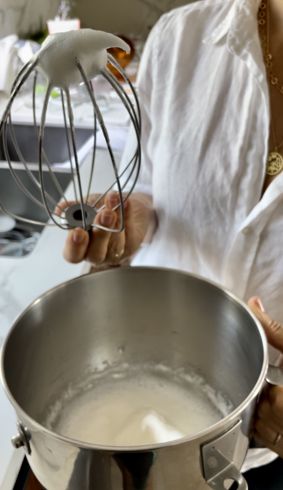 a hand holding a whisk to show the stiff peaks of egg whites