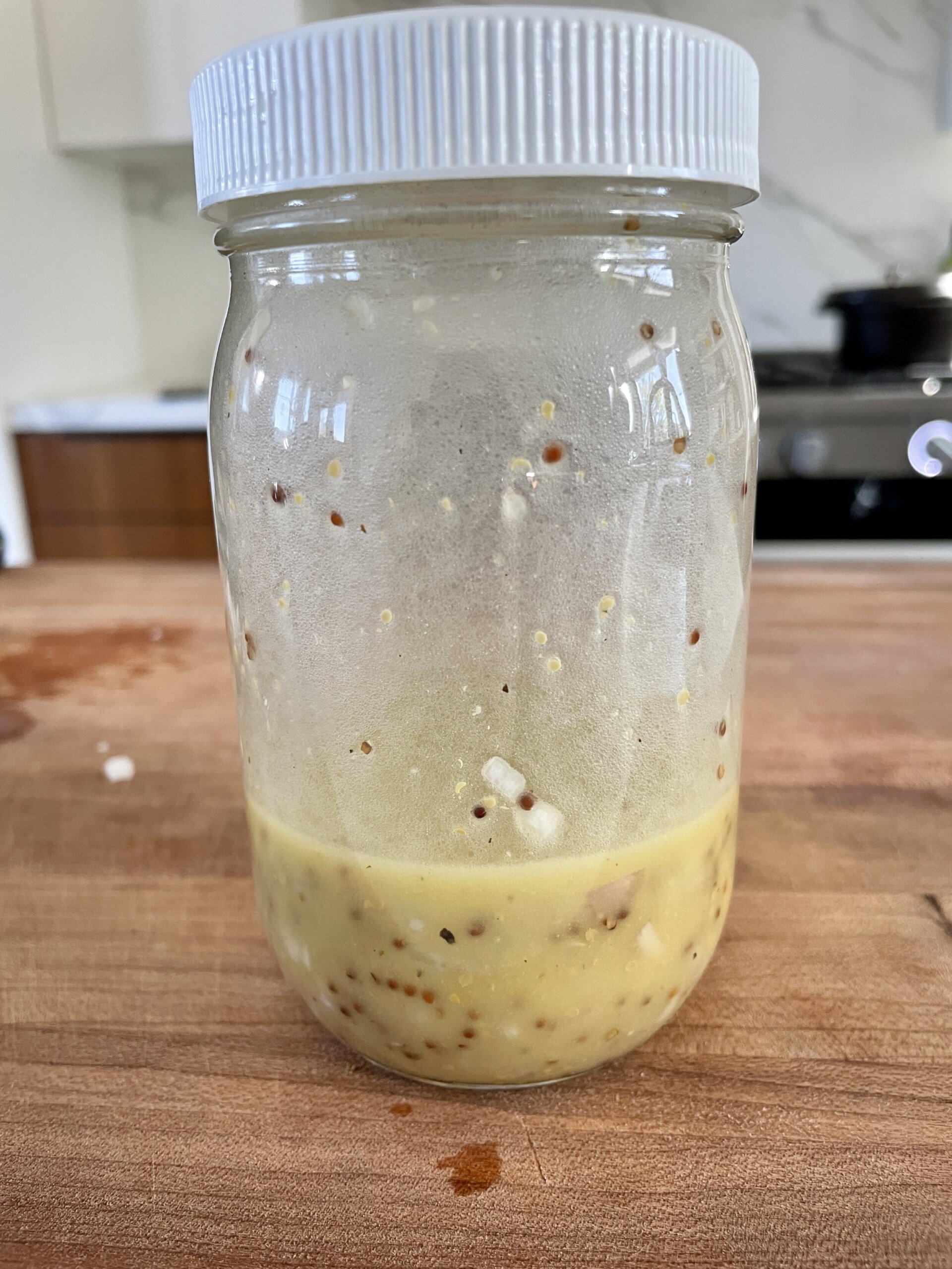 Vinaigrette ingredients in a glass jar with a screw top lid, ready to be mixed for dandelion salad dressing.