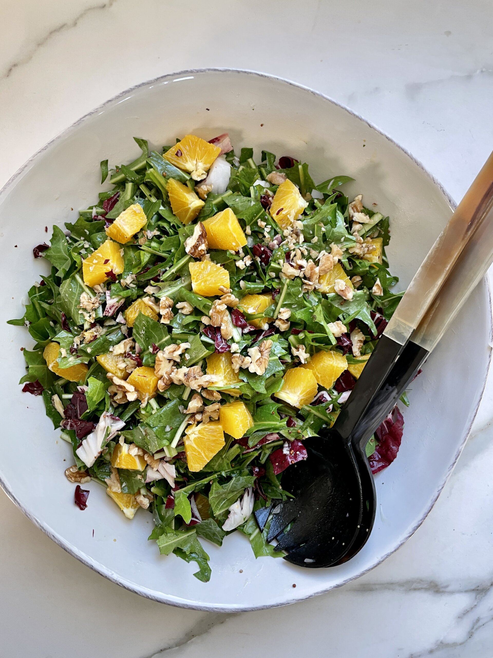 Close-up of a colorful dandelion salad with radicchio, greens, edible flowers, and bright citrus dressing.