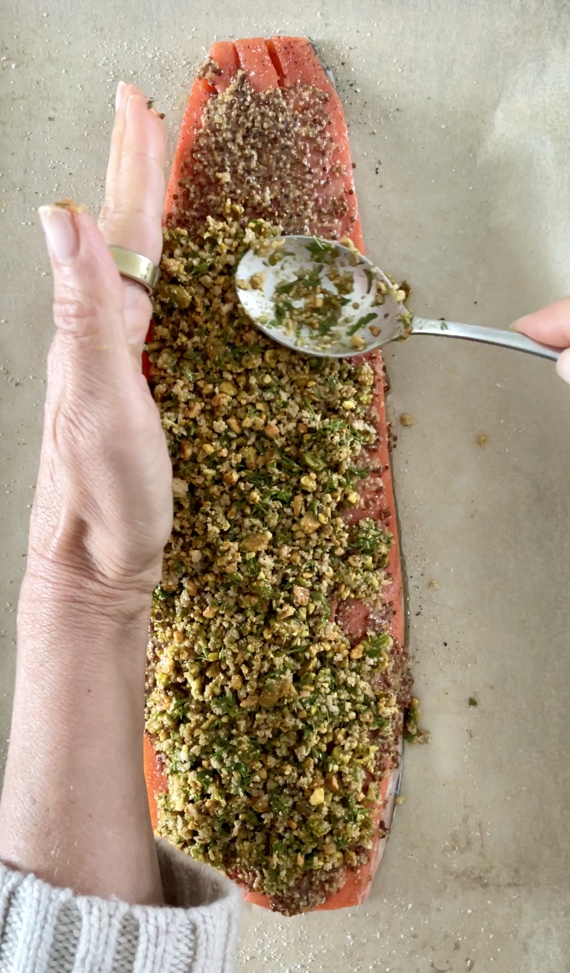 spooning the pistachio crumb mixture on to a salmon filet