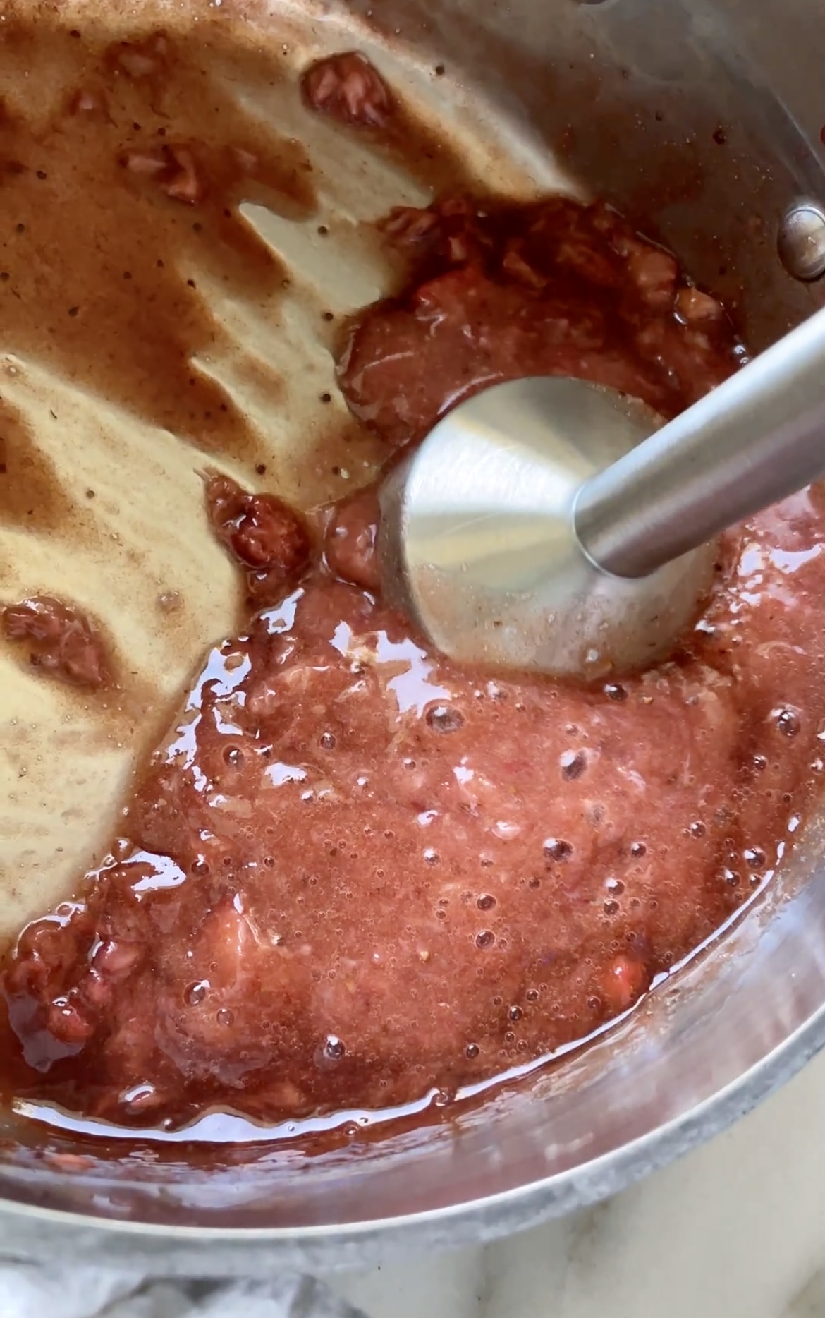 blending cooked strawberries with immersion blender