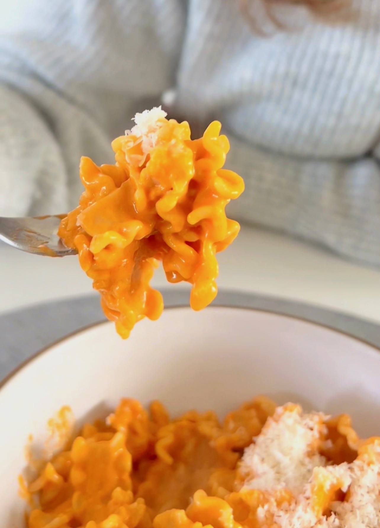 Close-up of creamy vodka pasta with tomato sauce and fresh basil in a white bowl