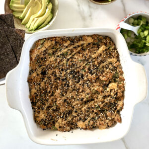 an overhead shot of a salmon sushi bake next to bowls of toppings