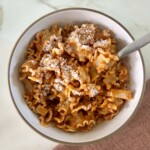 vodka pasta recipe in a white bowl with a fork and topped with parmesan cheese