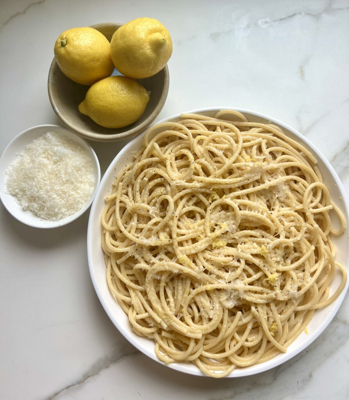 pasta al limone on a plate next to cheese and lemons