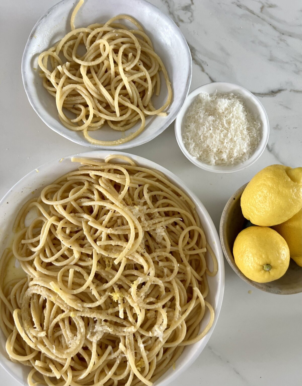 an overhead shot of pasta in a white bowl topped with parmesan cheese