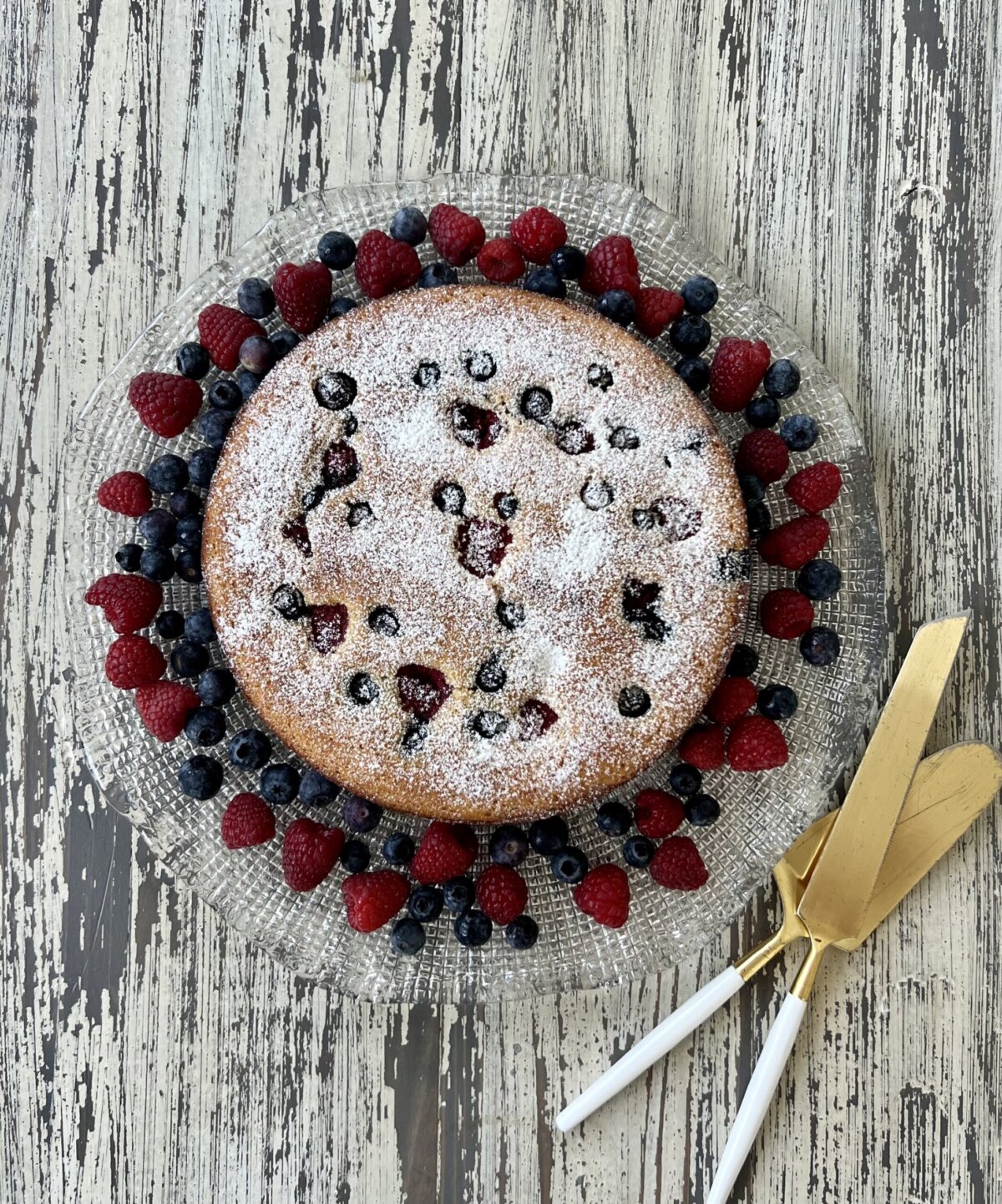 an overhead shot of a ricotta cake topped with berries and powdered sugar