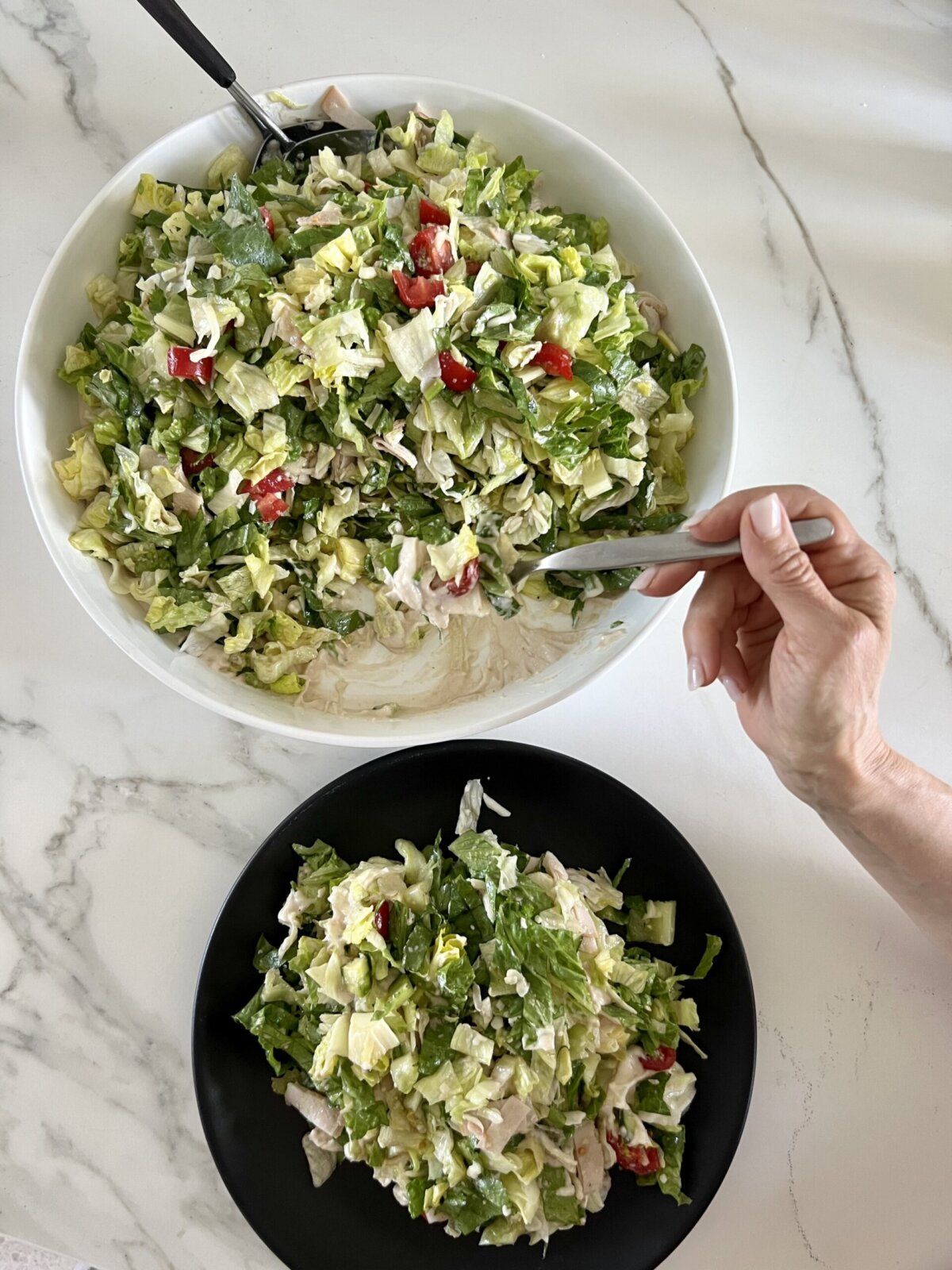 a large serving bowl of salad next to a plate