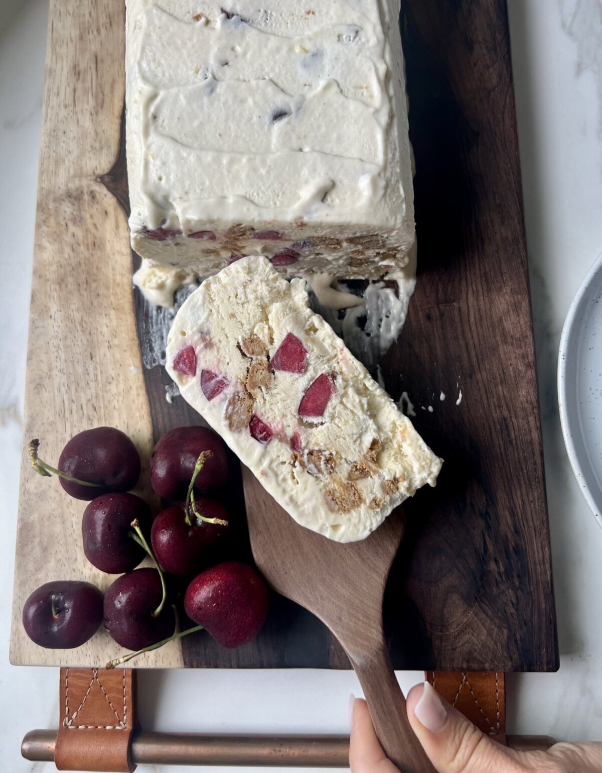 a slice of semifreddo with cherries and cookies inside. 