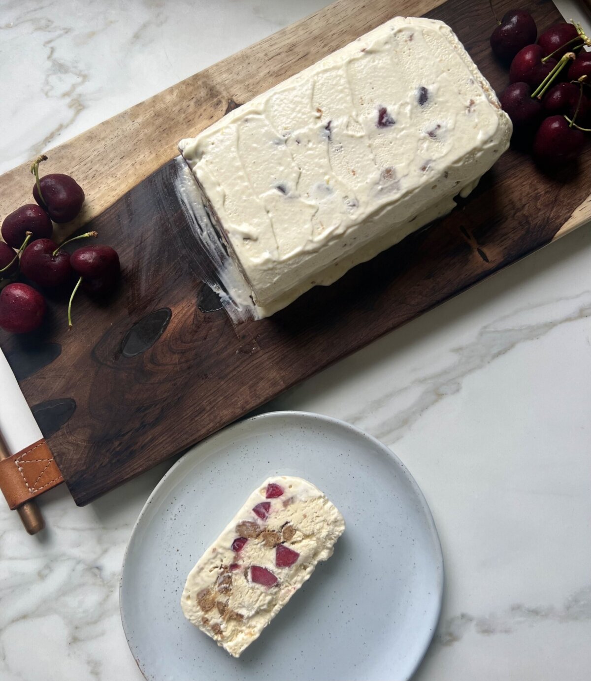 a slice of semifreddo on a plate next to a loaf on a cutting board