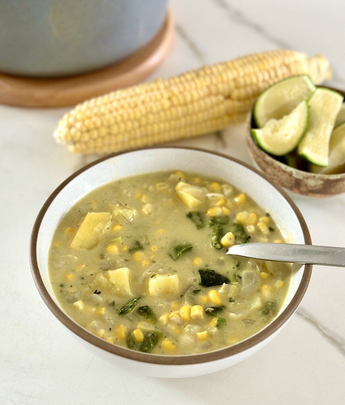 a side view of roasted poblano soup next to a corn cob