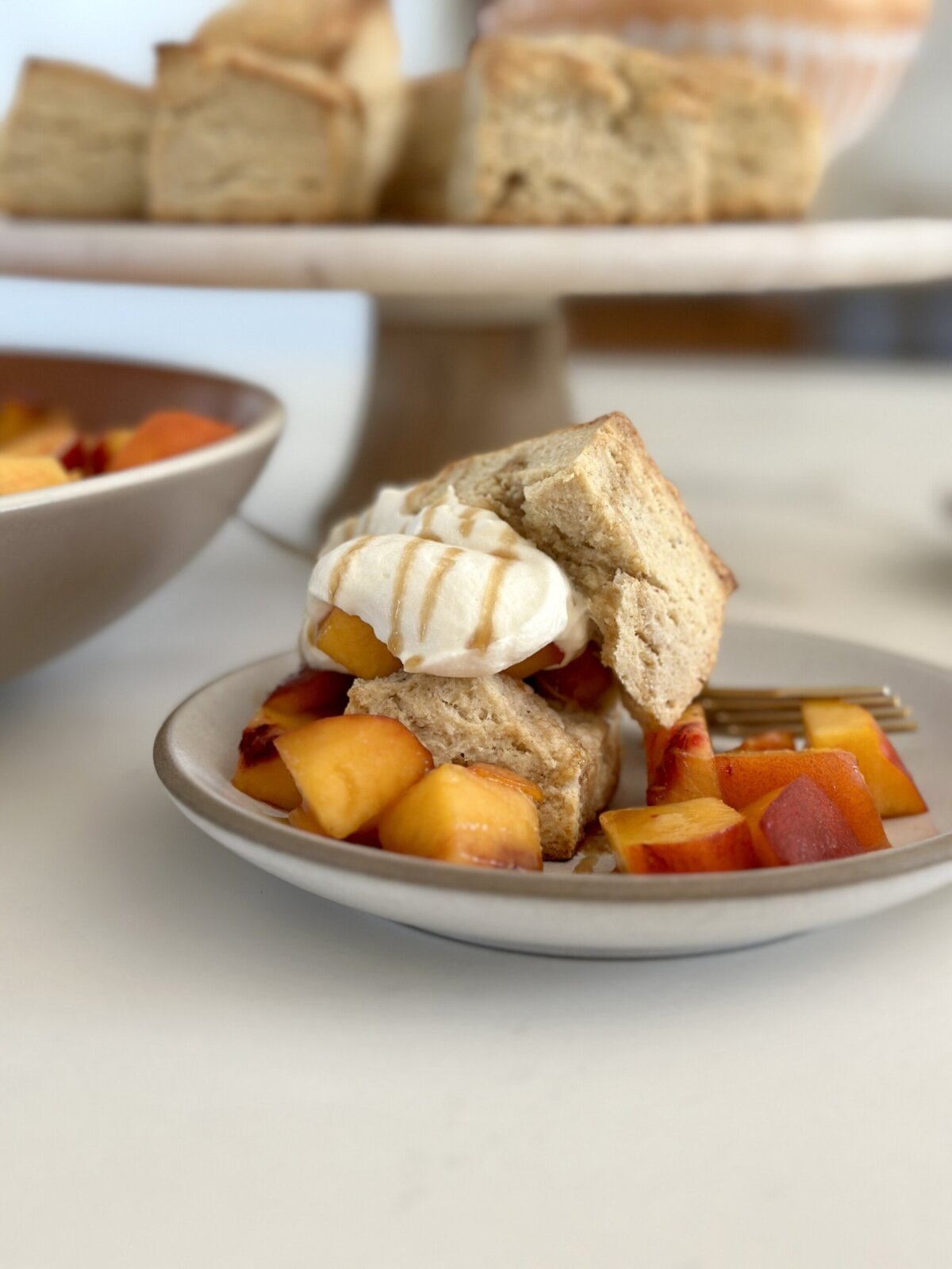 an up close photo of peach shortcake on a plate topped with whipped cream