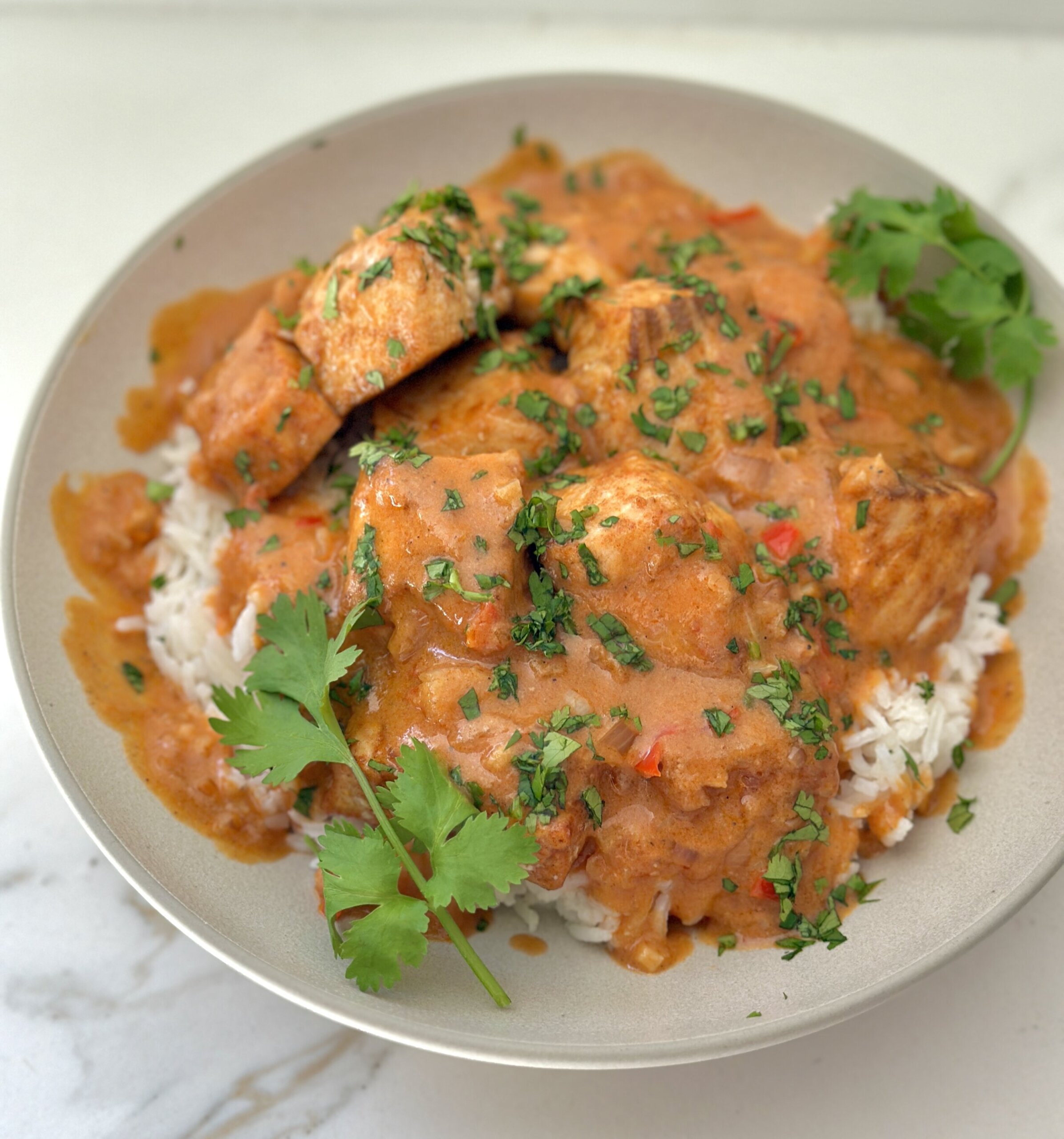 oven roasted salmon in a bowl with white rice and coconut tomato sauce