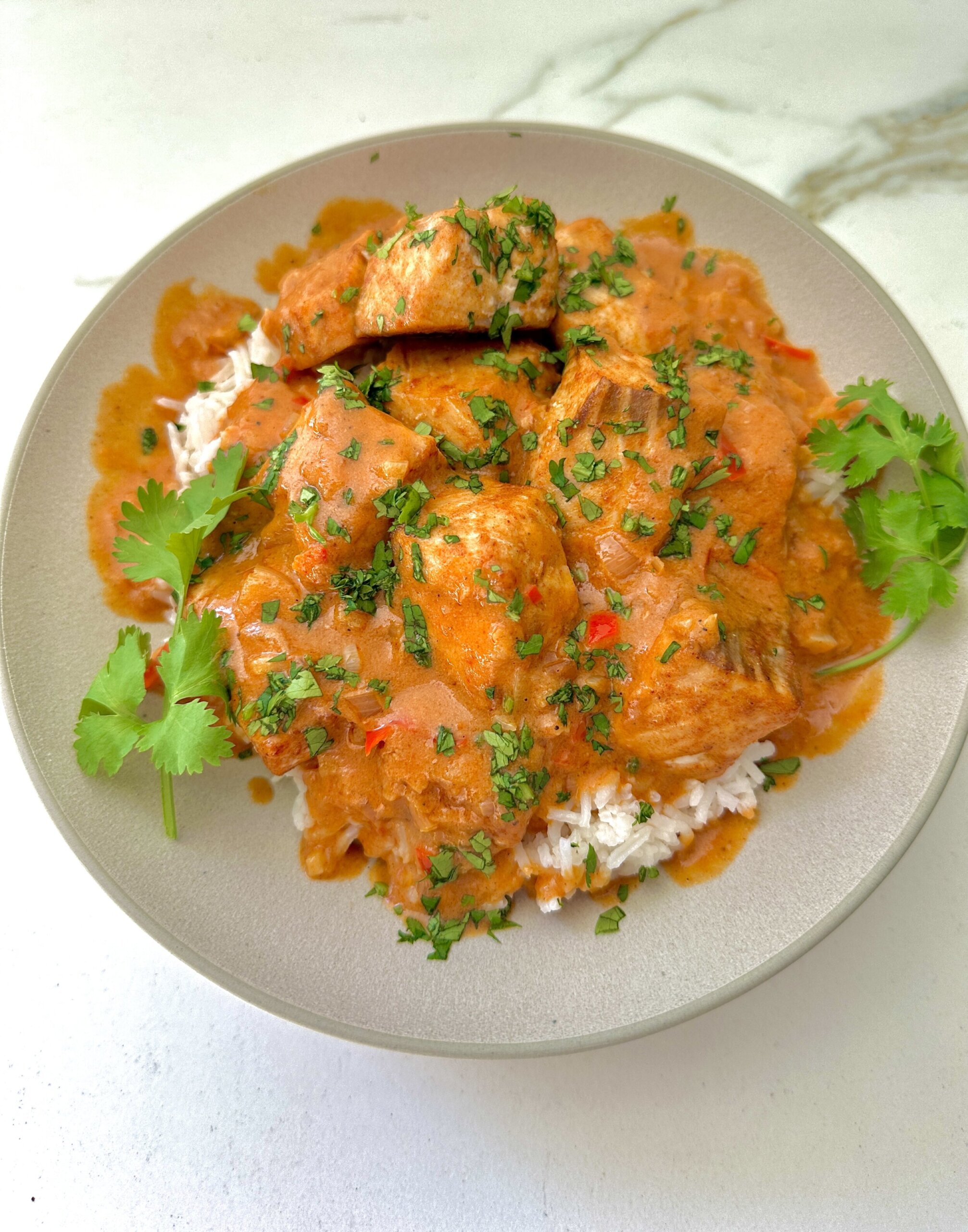 oven roasted salmon in a bowl topped with coconut tomato sauce