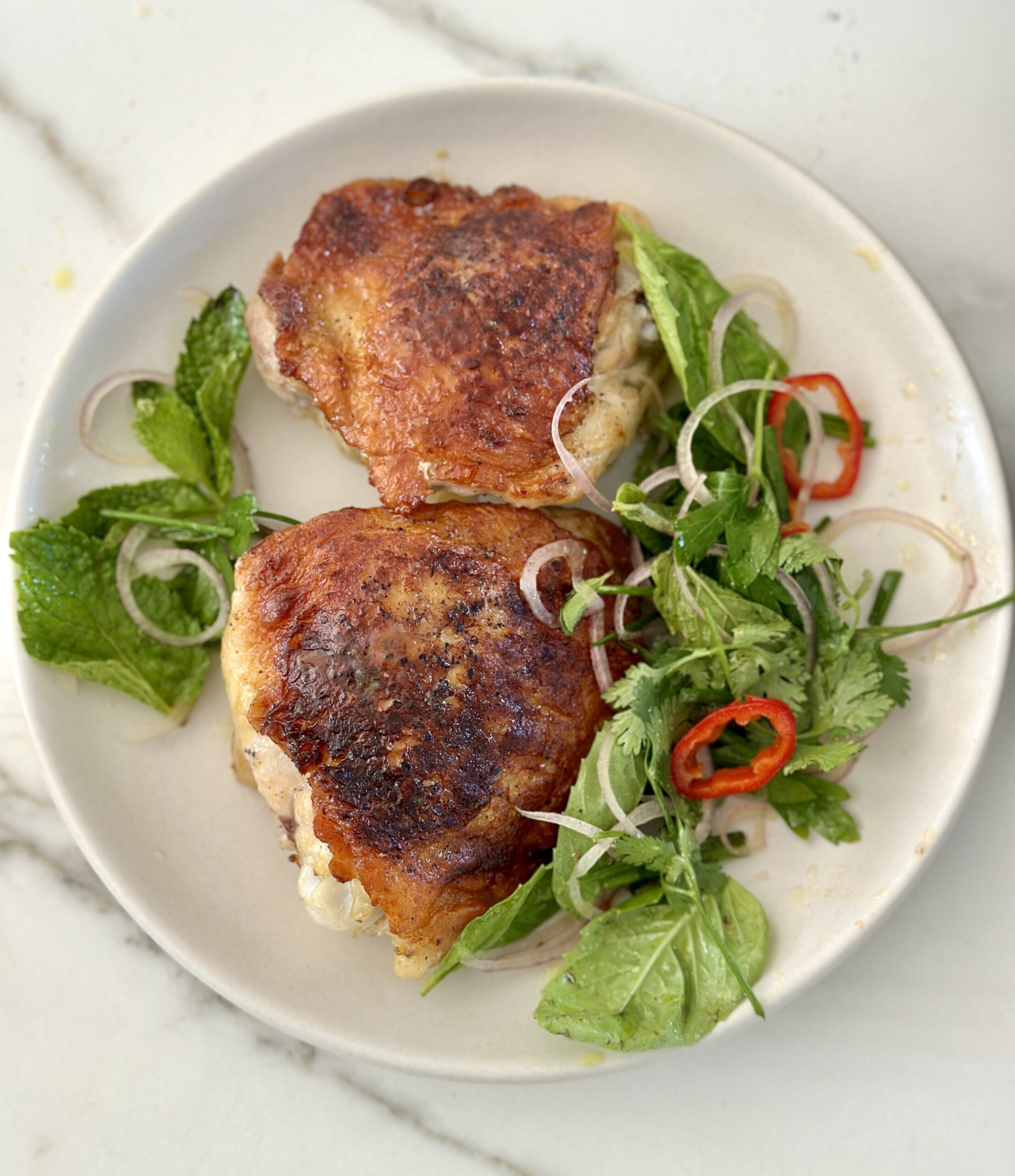 extra crispy chicken thighs on a plate with herb salad