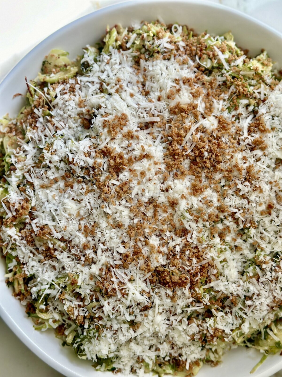 an overhead shot of brussels sprout caesar salad in a white bowl 