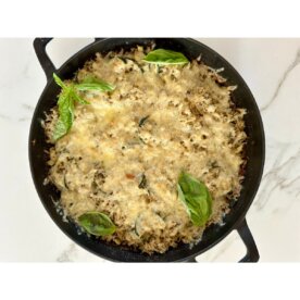 zucchini rice bake in a cast iron skillet topped with fresh basil