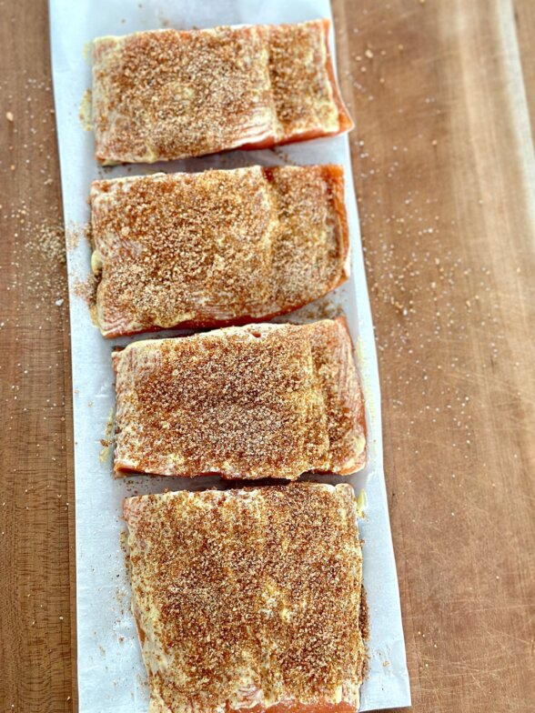 salmon rubbed with spices on a parchment lined baking sheet