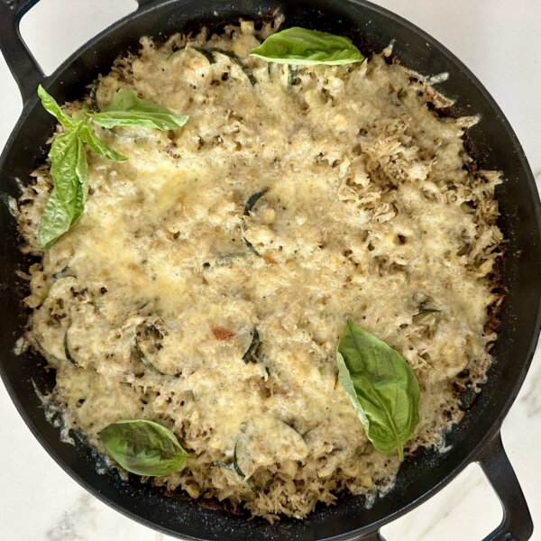 zucchini rice bake in a cast iron skillet topped with fresh basil