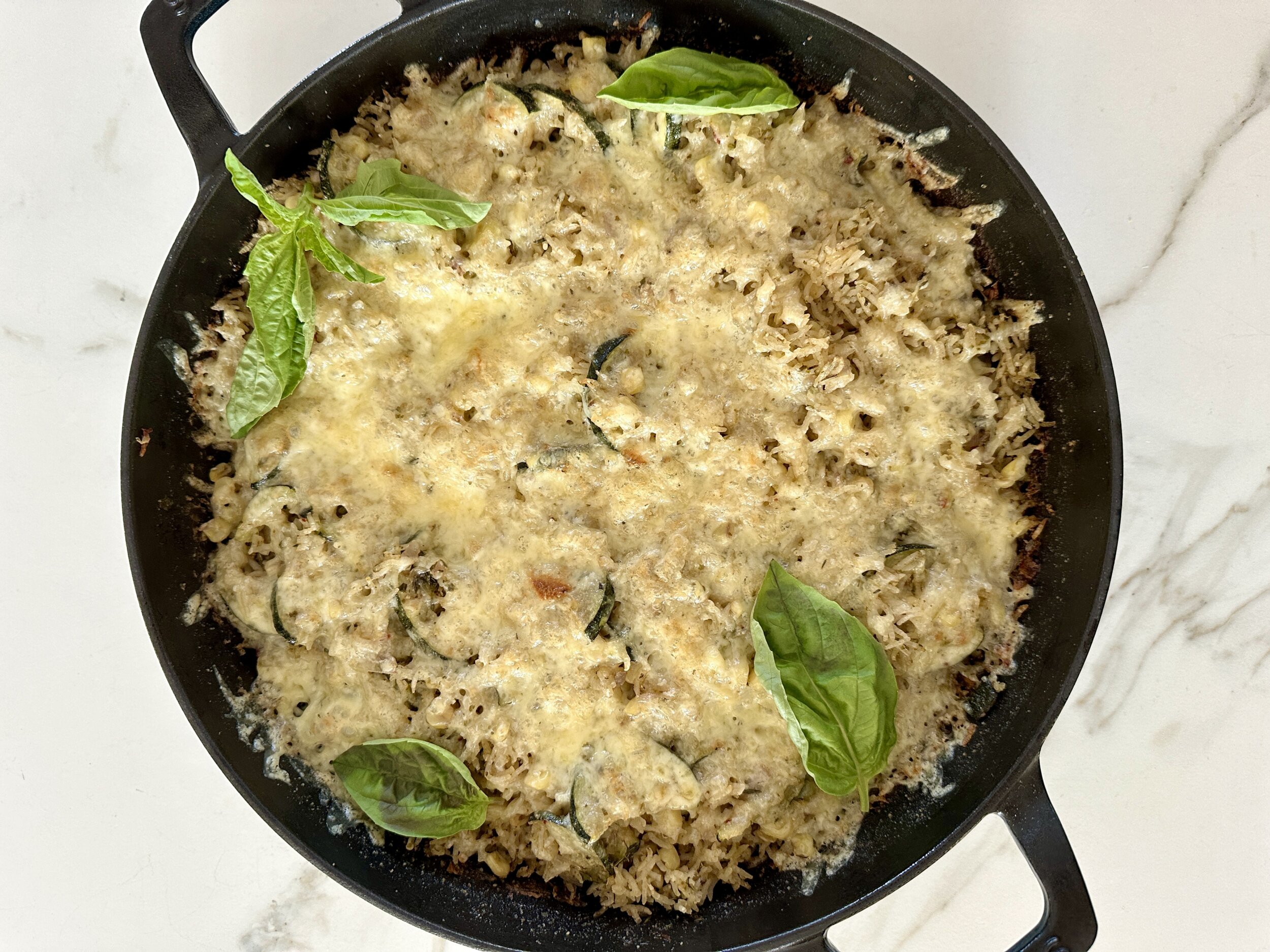 zucchini rice bake in a cast iron skillet topped with fresh basil