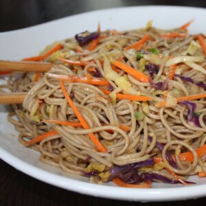 asian noodle salad with chopsticks in a white bowl