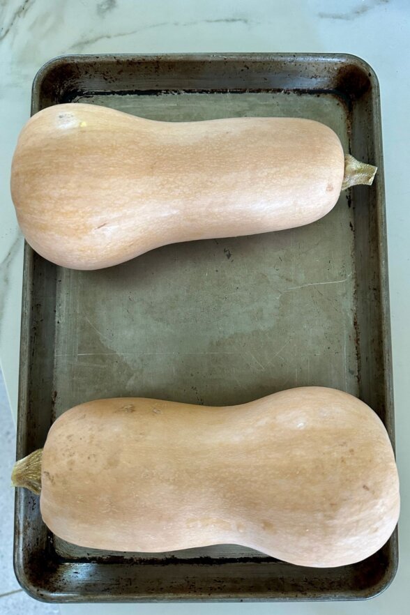 butternut squash cut in half on a baking sheet