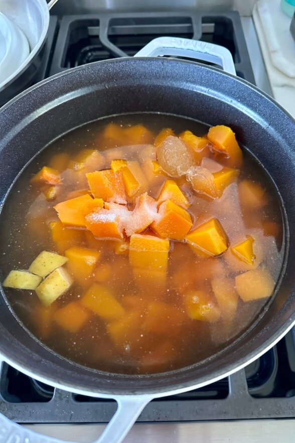 veggies covered in broth in a soup pot