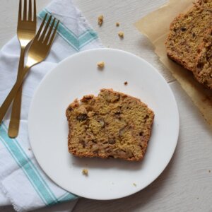 piece of date sweetened banana bread on a white plate by two forks