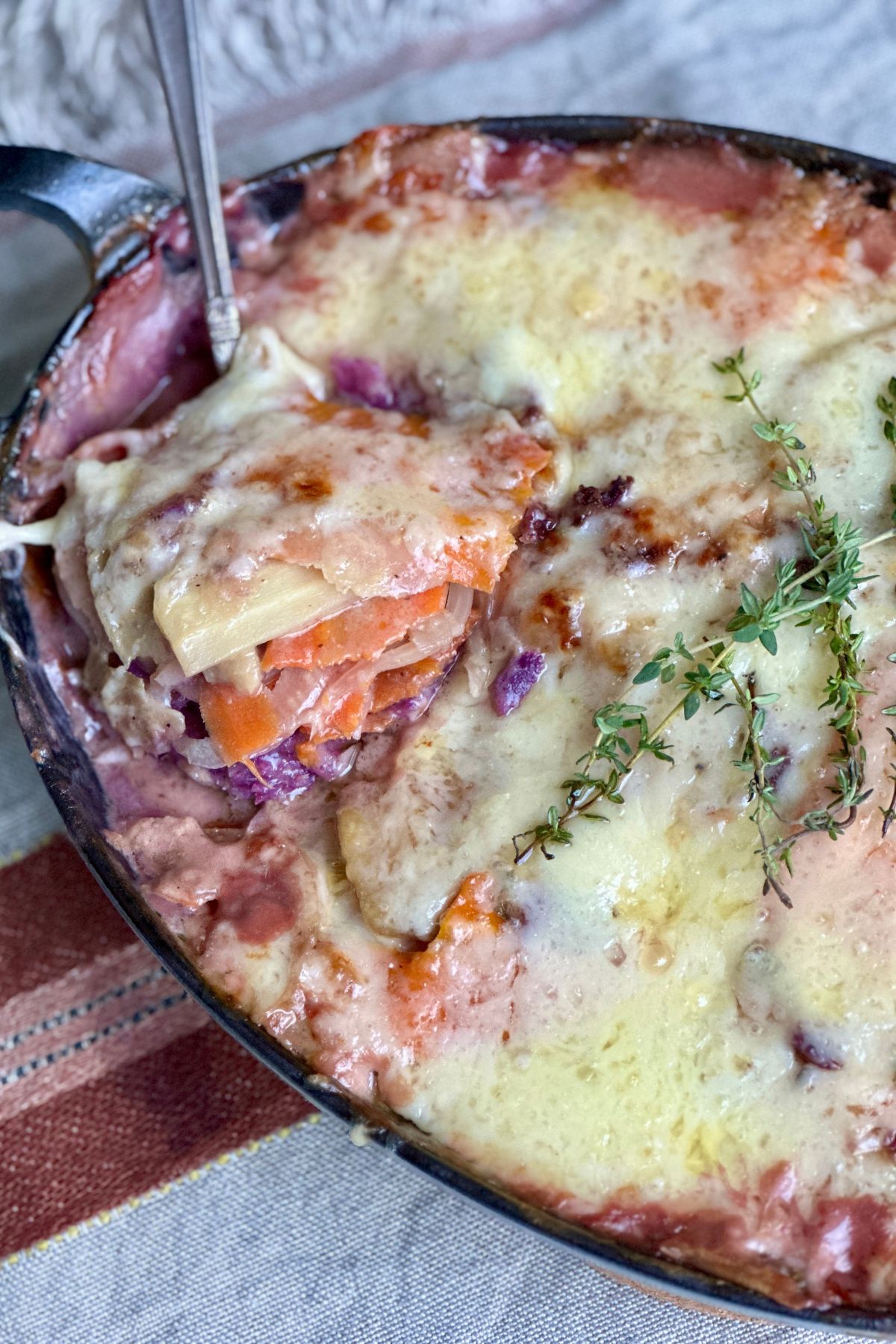 scooping a serving of root vegetables out of a baking dish 