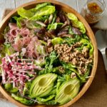 thanksgiving salad in a bowl topped with pomegranate vinaigrette