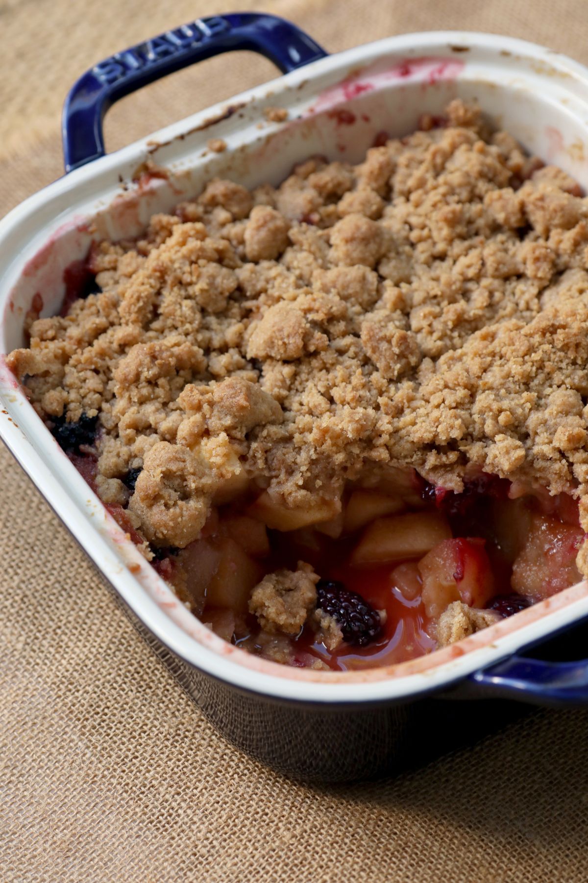 a scoop of apple blackberry crumble taken out of the baking dish