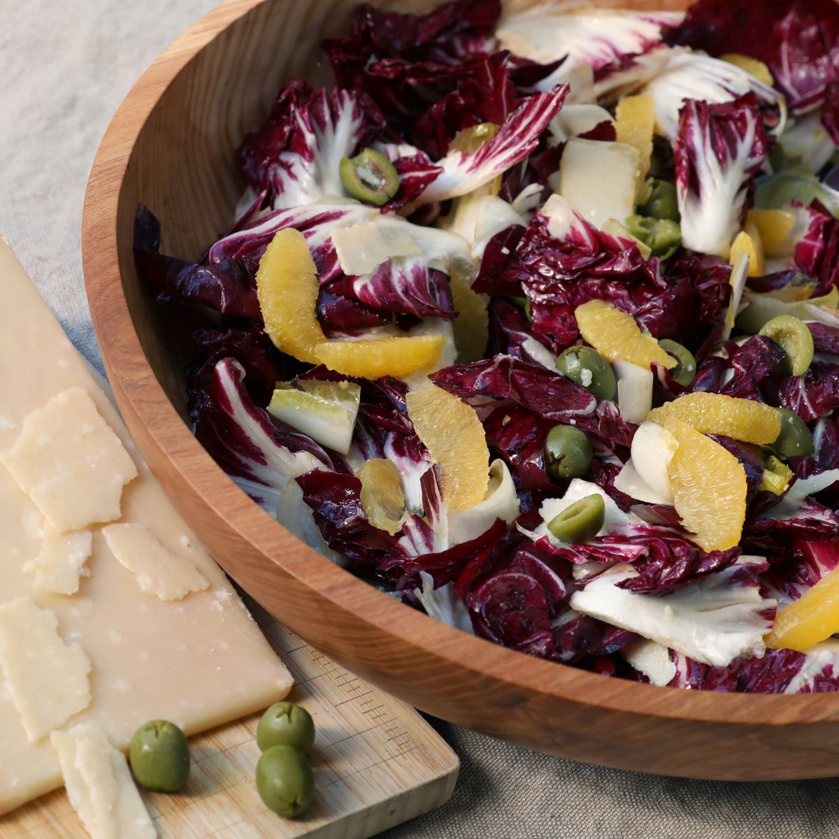 bowl of red radicchio and endives salad topped with parmesan cheese, olives, and oranges