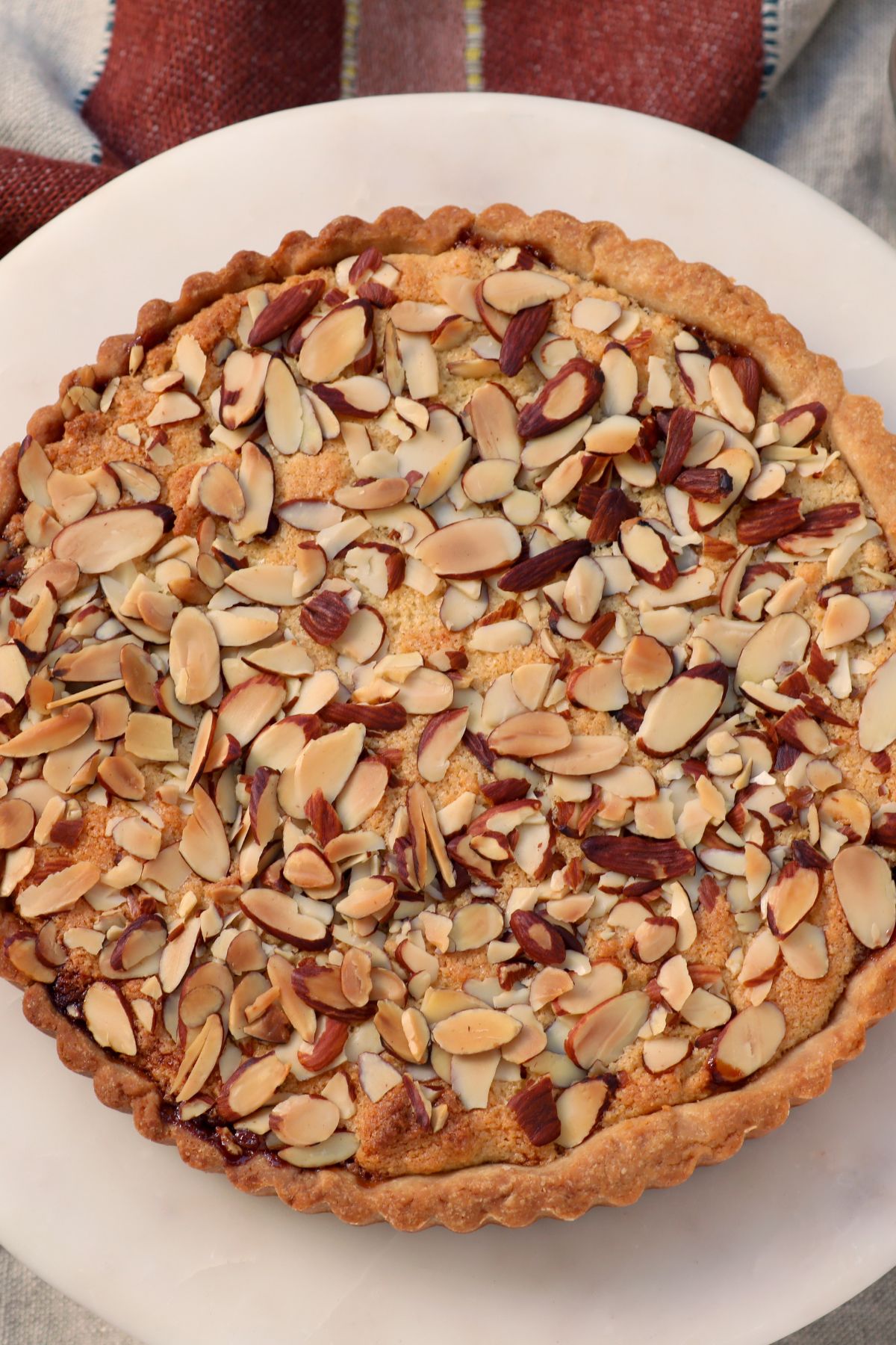 cherry bakewell tart baked and placed on top of a cake stand