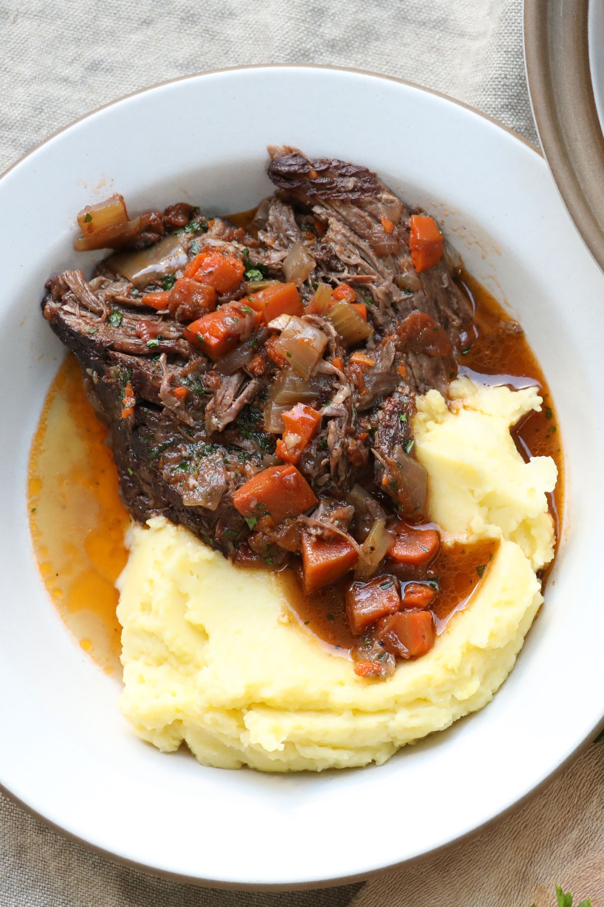 beef next to a side of mashed potatoes on a white plate