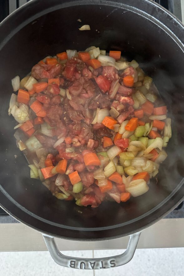 adding tomatoes and red wine to the pot